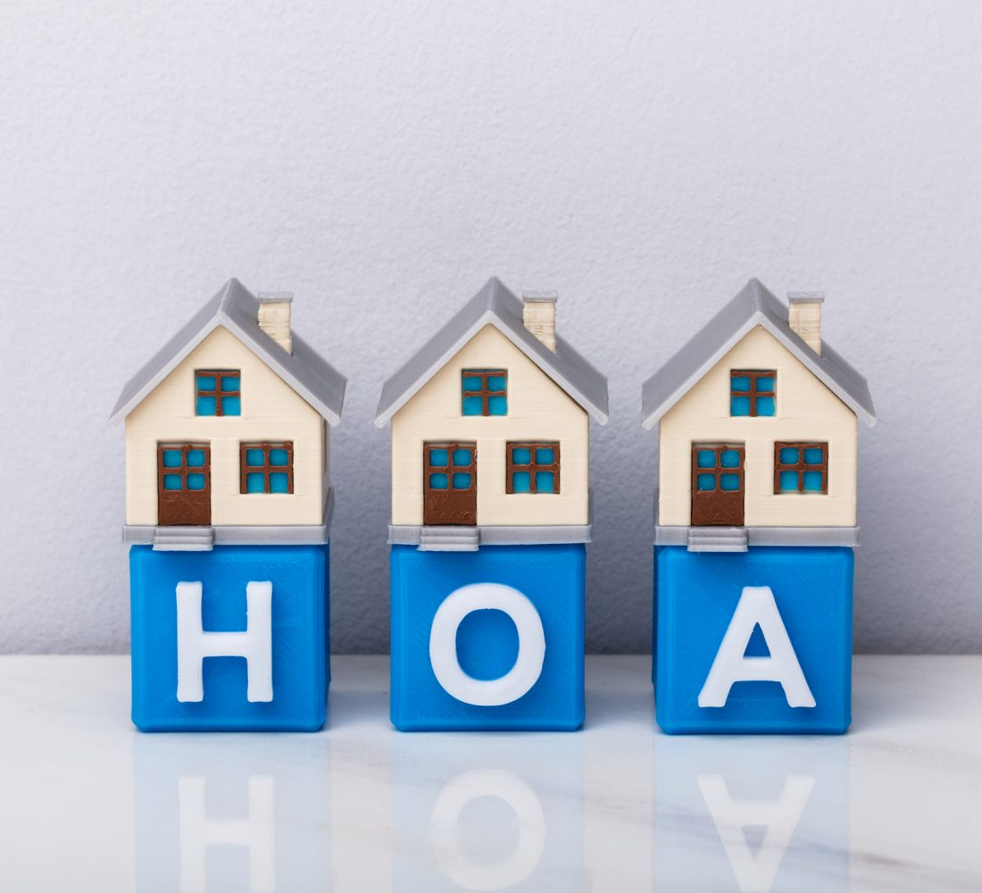 Row Of House Models On Blue HOA Cubic Blocks Over Reflective Desk