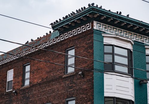 Toronto, ON 12/27/2019: Parkdale scene of gritty old ornate brick apartment building with pigeons sitting in a row.